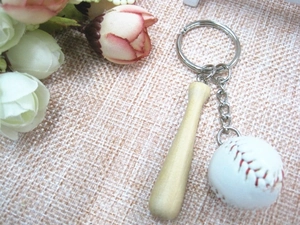 Detail of mini wooden baseball bat and white softball keychain with metal ring