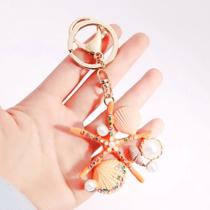 Porte-clés étoile de mer et coquillage avec perles et strass tenu à la main