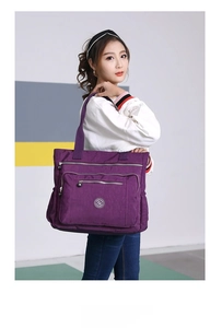 Side view of large purple nylon tote bag with multiple zippers shown on a female model