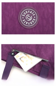 Detail of purple nylon tote featuring brand logo patch and rear anti-theft zipper pocket