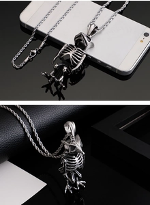 Macro view of a silver owl skeleton pendant with a twisted chain on a black reflective surface