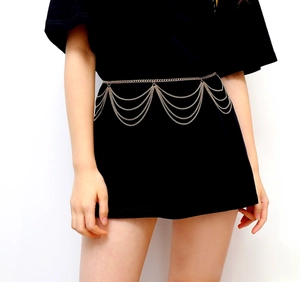 Detailed close-up of multilayered gold body chain with elegant fringe tassels on model