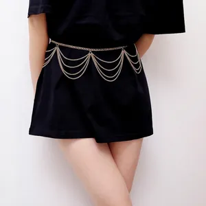 Detail view of multi-layer gold chain waist belt with cascading fringe on black dress