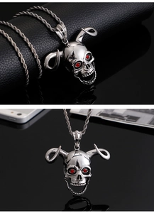 Detailed view of silver skull pendant with curved horns and red gemstone eyes