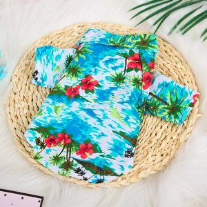 Blue Hawaiian dog shirt with tropical palm tree print on a woven straw mat and white fur