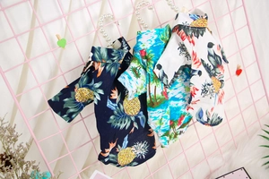 Three tropical pet shirts with pineapple and palm prints on pearl hangers