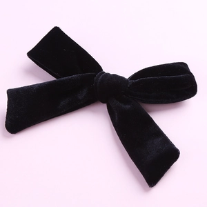 Detail of 5-inch black velvet hair bow clip with soft texture on a pastel background