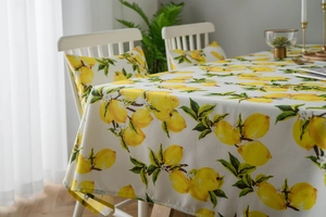 Detail of fresh yellow lemon print tablecloth and matching cushion in a bright dining room