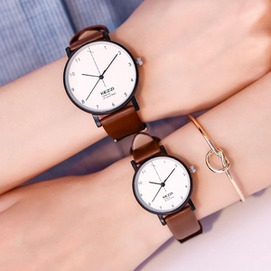 Close-up of Kezzi minimalist couple watches with brown leather straps and white dials