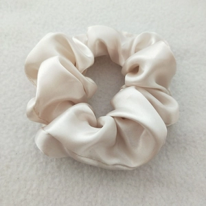 Detailed view of a white satin scrunchie with smooth texture and elegant silky luster