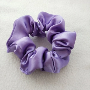 Close-up of smooth purple satin fabric scrunchie with a glossy silk texture finish