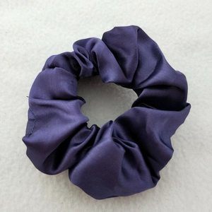 Close-up detail of a premium purple satin scrunchie with a glossy silk-like texture