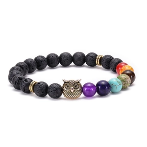Macro detail of lava stone bracelet with golden owl charm and colorful chakra beads