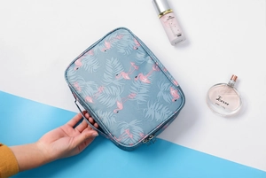 Detail of gray-blue flamingo makeup bag featuring waterproof fabric and top handle