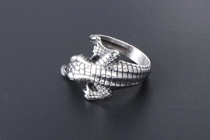 Macro shot of the detailed vintage silver crocodile ring on a textured grey background