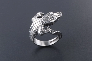 Macro shot of silver crocodile ring detailing fine carvings on dark textured surface