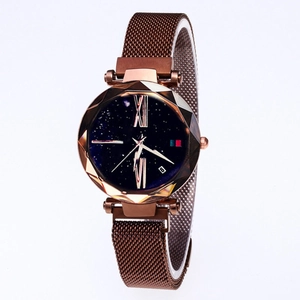 Detail of star-patterned watch face with faceted crystal and bronze mesh strap