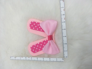 Detail of pink bow hair accessory with polka dots showing size on a measuring ruler