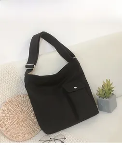 Detail van een zwarte canvas tas met verstelbare riem op een bank met accessoires