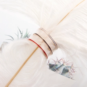 Three minimalist 1mm stainless steel stacking rings in red, black, and silver on a white feather