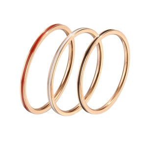 Three stacked minimalist 1mm rose gold rings with red, white, and black enamel drip