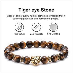 Macro shot of tiger eye stone beads with a golden leopard head charm on white background
