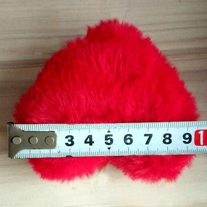 Detail showing the 10cm width measurement of the red plush heart keychain with a tape measure
