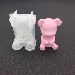 Detail of bear silicone mold and pink resin bear statue on black leather background