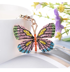 Detailed close-up of a golden butterfly keychain with colorful rhinestones on a ceramic cup