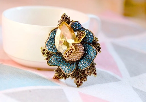 Detail of vintage flower brooch with blue rhinestones and amber crystal on ceramic