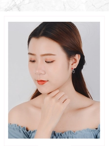 Close-up of minimalist silver heart gesture stud earrings worn on a woman ear