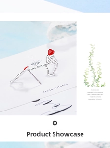 Close-up of silver finger heart stud earrings with red enamel hearts on display card