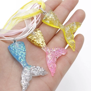 Detail of colorful resin mermaid tail pendants with shimmering sequins and silk ribbons