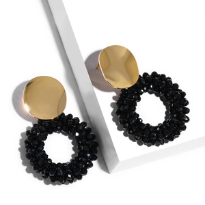 Detail of elegant gold disc earrings featuring a hanging circle of black faceted beads
