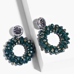 Macro view of handmade beaded hoop earrings with green crystals and rhinestone studs