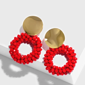 Close-up of red beaded hoop earrings with gold metal studs on a white display stand