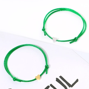 Detail view of adjustable green woven bracelets with gold and silver heart charms