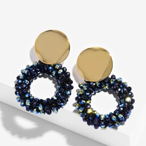 Detail shot of golden round sequins and deep blue faceted beads on large hoop earrings