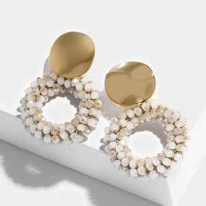 Close-up of bohemian gold earrings with woven faceted cream crystal bead hoops