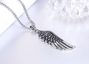 Detailed view of vintage silver feather wing pendant and square link chain on metal surface