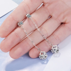 Silver drop earrings with long chain and geometric crystal cube held in hand