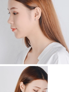 Detailed view of silver cross-star stud earrings worn on ear in minimalist style
