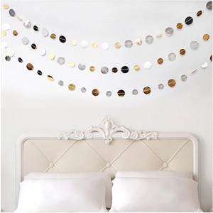 Close-up of gold, silver, and black circular paper garlands hanging on a white wall