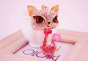 Macro detail of cute cat keychain with pink rhinestones and gold enamel finish
