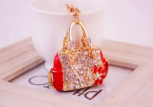 Close-up of golden metal handbag keychain with red enamel flowers and crystal rhinestones