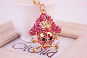 Macro shot of gold pirate skull keychain featuring pink rhinestones and crown detail