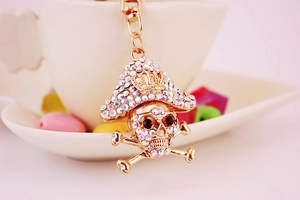 Close-up of golden pirate skull keychain with sparkling crystals and a mini crown detail