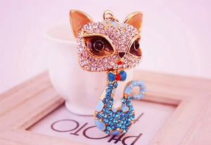 Close-up of sparkling rhinestone fox keychain with blue enamel details and gold plating