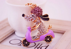 Macro shot of rhinestone dog riding motorcycle keychain with purple sparkling crystals