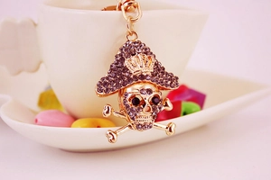 Detailed close-up of a sparkling rhinestone-studded golden pirate skull metal keychain